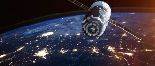 A satellite in space with the moon and earth in the background.